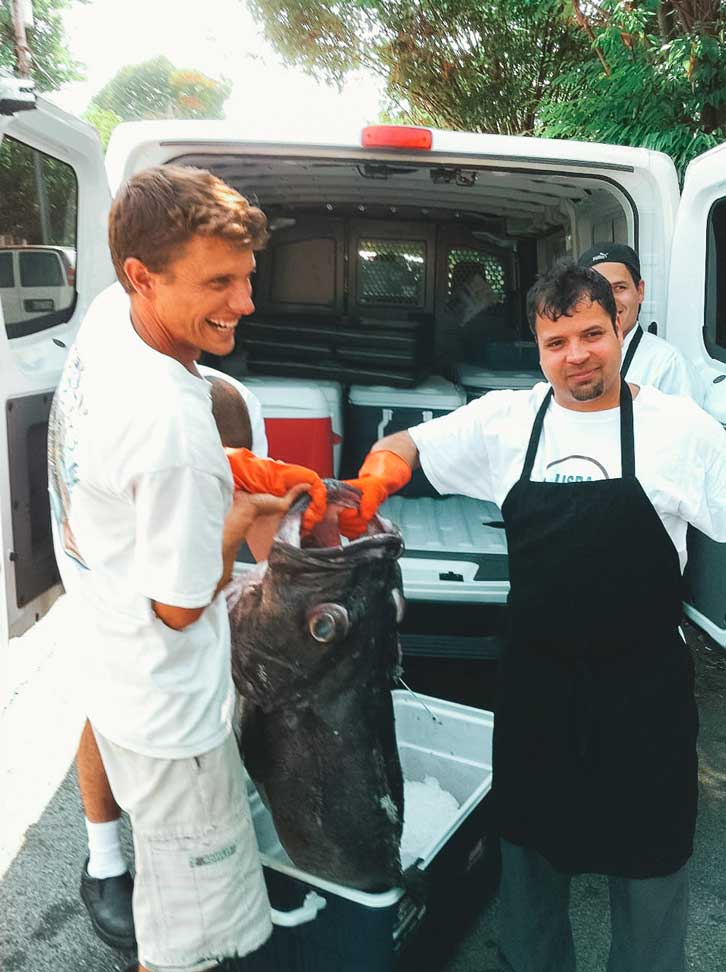Kelly holding up a Wreckfish in front of the back of a delivery van