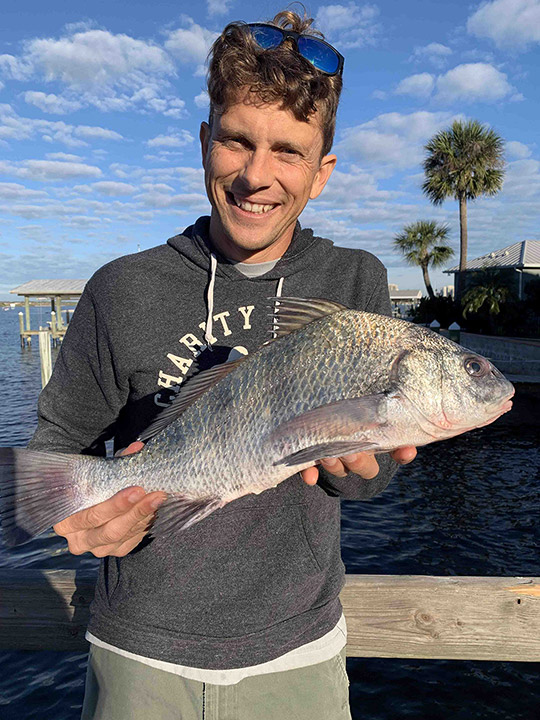 Kelly holding up a small black drum on a Florida pier