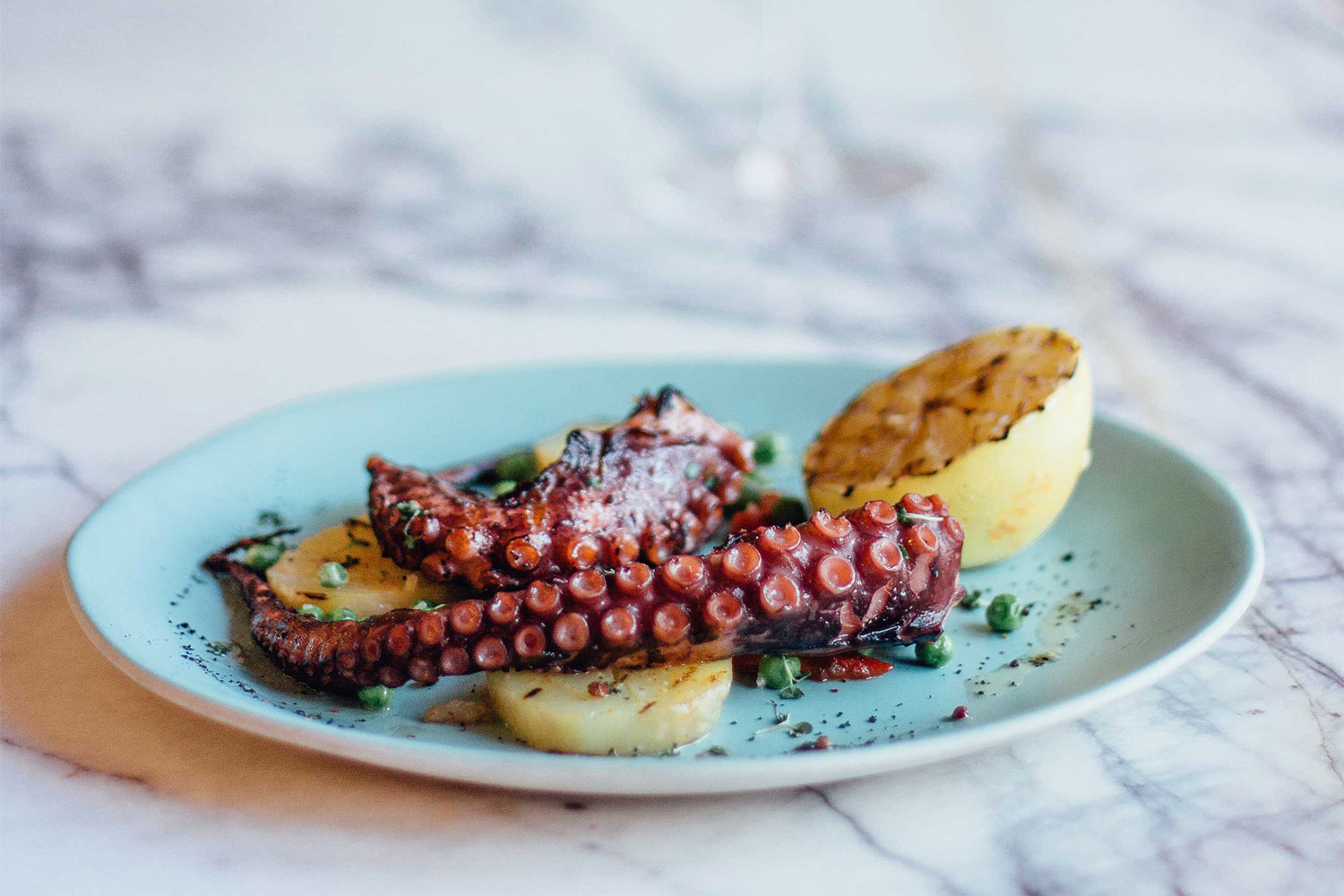 Grilled octopus on a blue plate with a grilled lemon